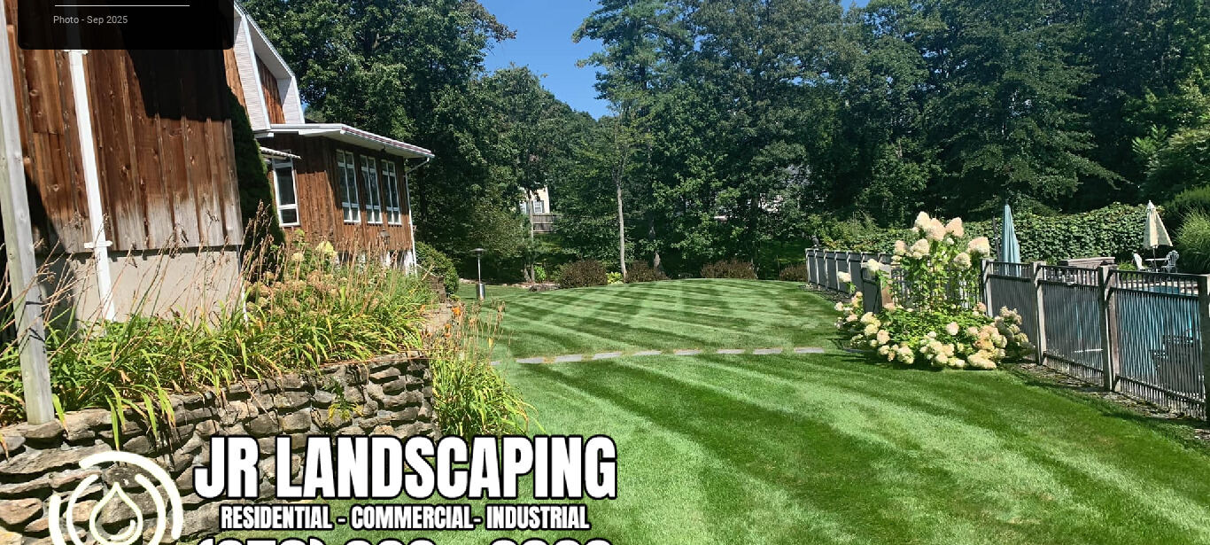 Freshly mown lawn with crisp mowing stripes leading to a fenced deck area